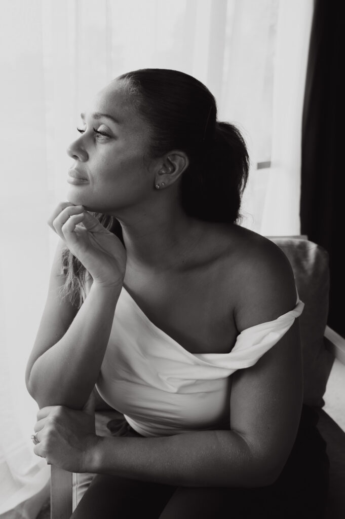 Black and white portrait of woman seated by a window during Aesthetics brand photoshoot