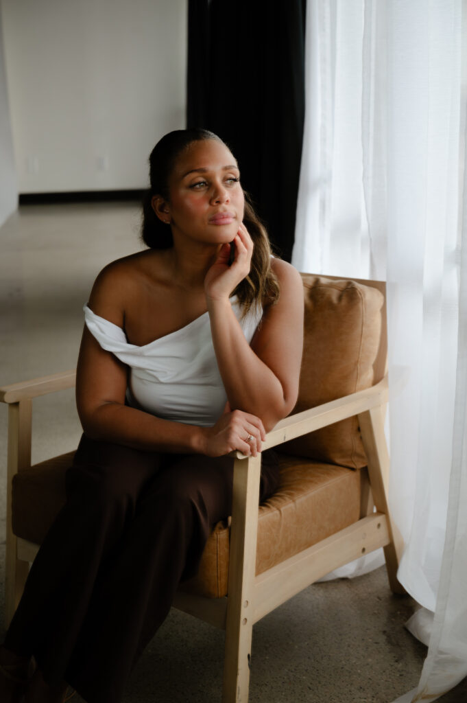woman seated by a window in a minimalist studio for brand session