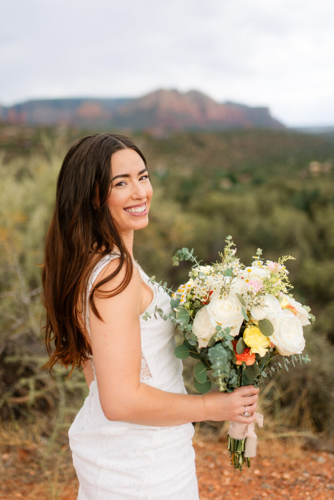 Bride smiling with bouquet at Sedona red rock overlook