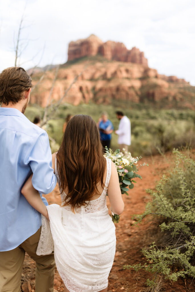 Bride walking to ceremony site holding bouquet in Sedona