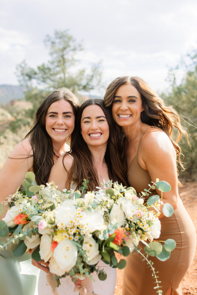 Three women smiling and holding bouquets during a Sedona elopement