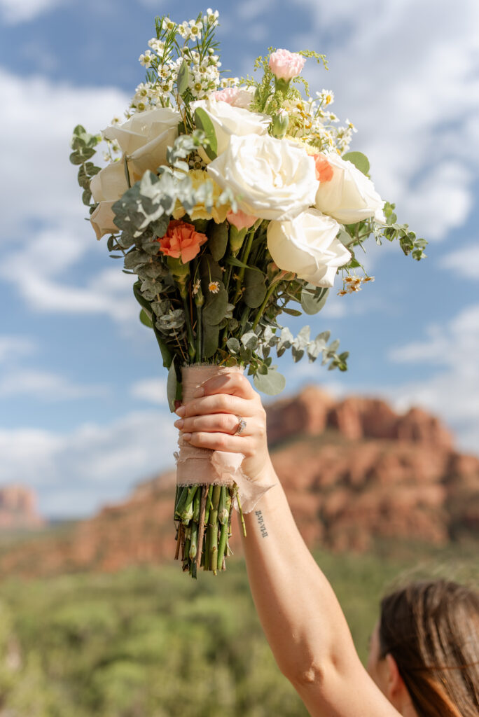 Bride holding bouquet up with Sedona red rock mountains in the background