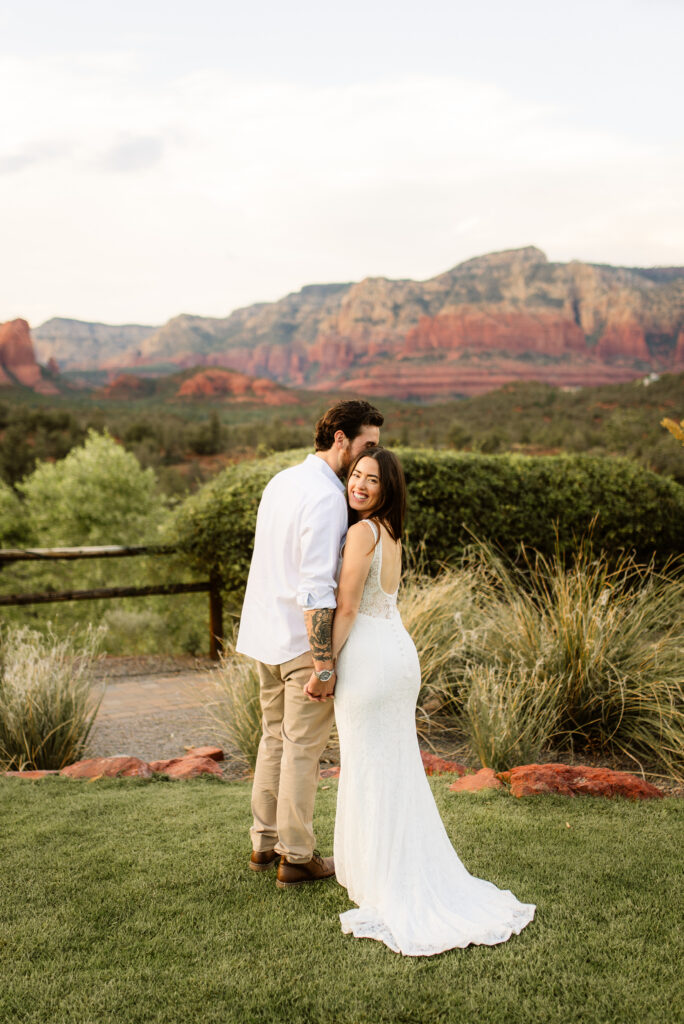 Bride and groom standing together with Sedona red rock view at sunset