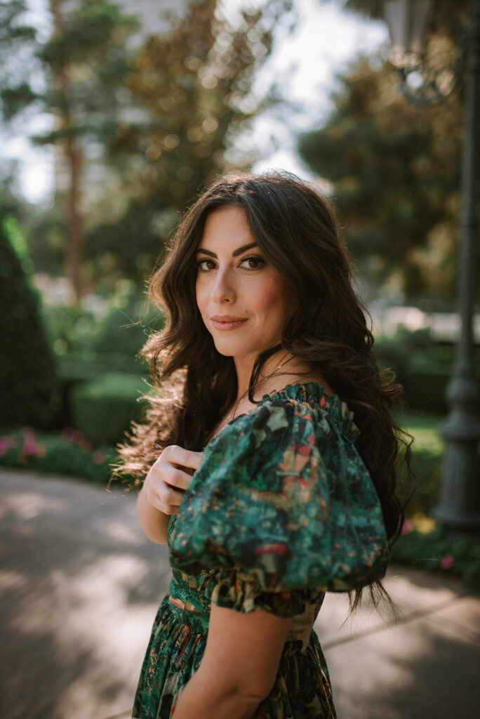 Woman in a green dress posing near the Bellagio gardens with soft afternoon light.