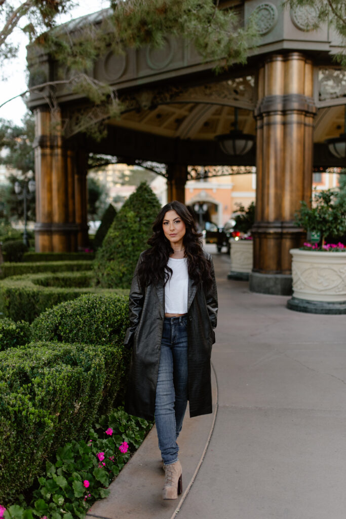 Full body portrait outside the Bellagio with greenery and classic architecture in Las Vegas.