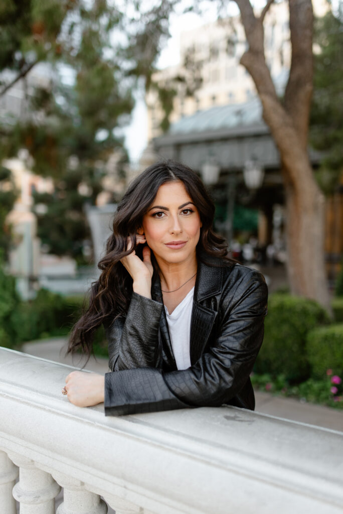 Woman in a black jacket leaning on a railing outside the Bellagio in Las Vegas.