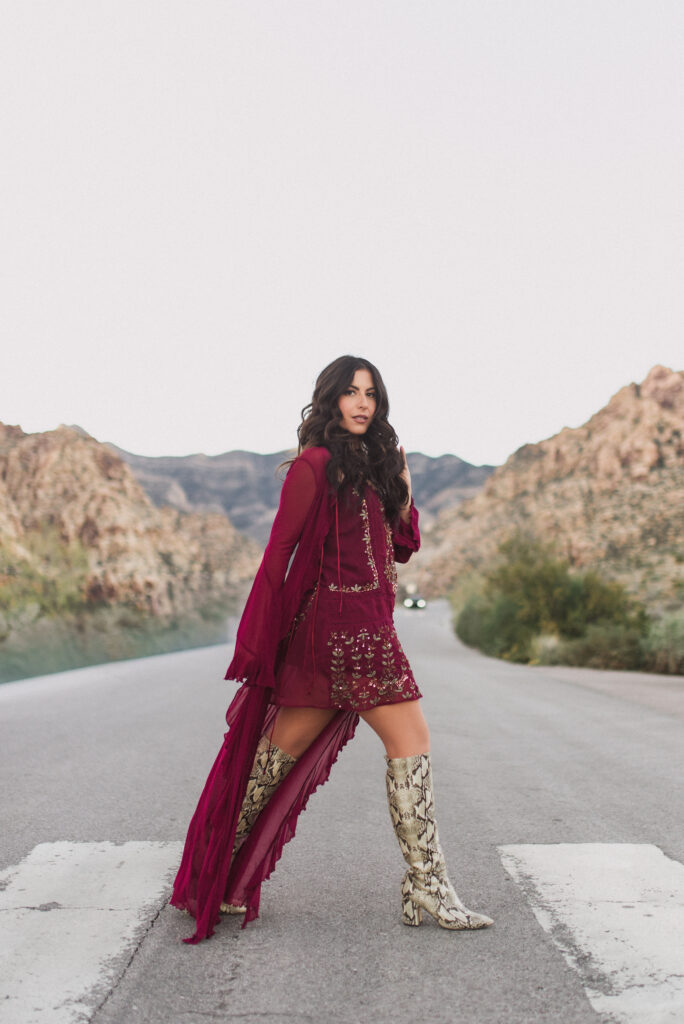 Woman in a burgundy outfit posing on a desert road near Red Rock Canyon, Las Vegas.